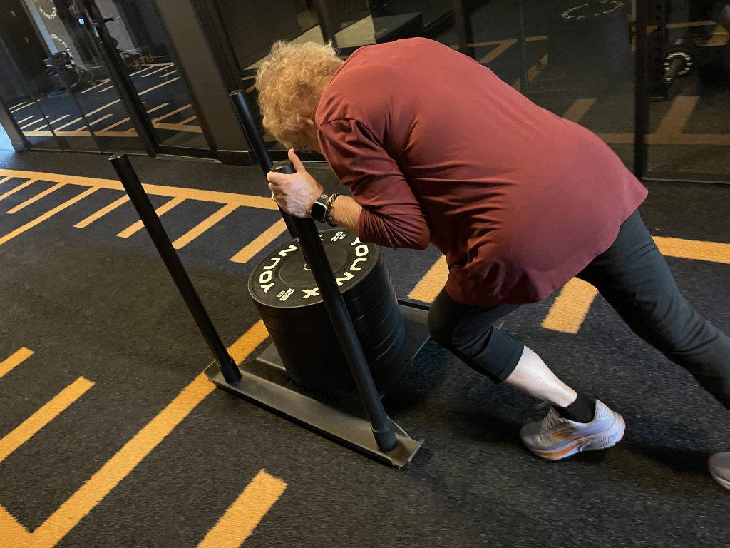 Client pushing a weighted sled during strength training