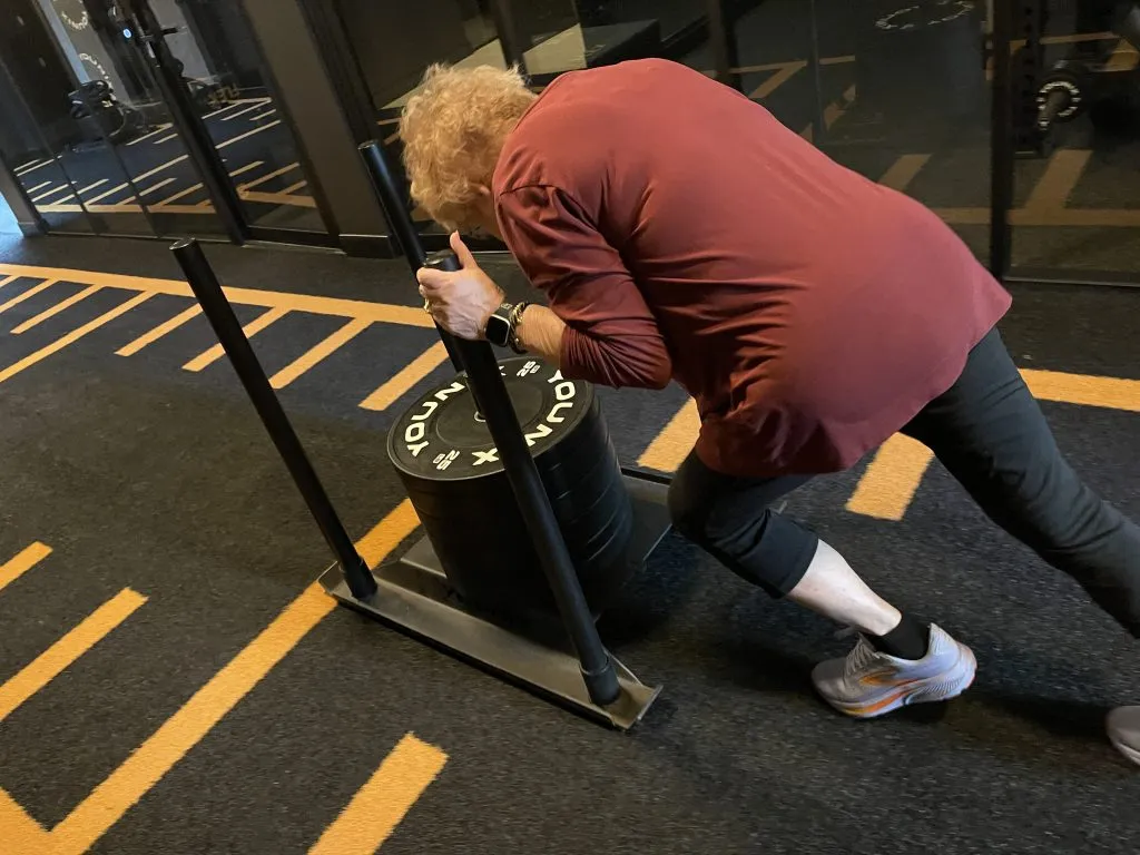 Client pushing a weighted sled during strength training